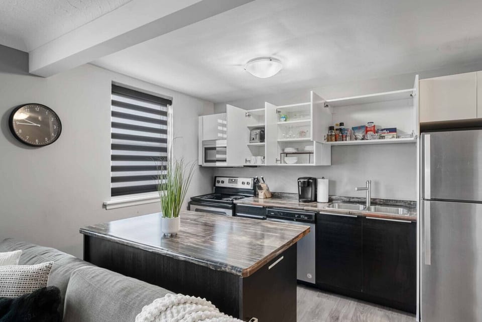 Cook and dine in our fully equipped kitchen! Features a spacious island, modern appliances including a stove, oven, microwave, and fridge. Stocked with essentials, coffee maker, and ample storage. Stylish blinds and a clock complete this functional space