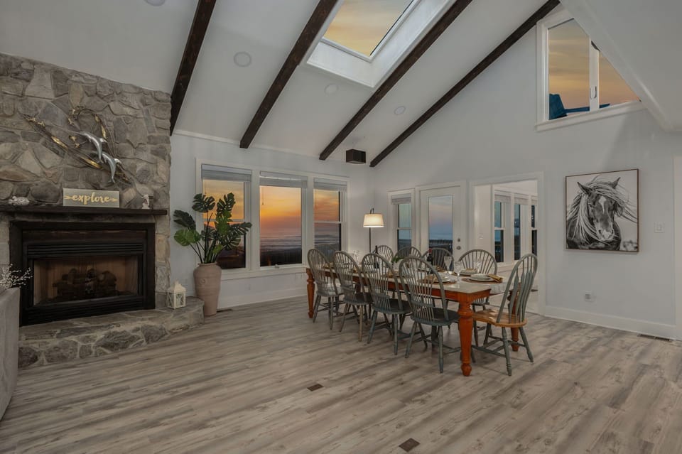 Mid Level: Dining Area with large table seating and expansive windows offering stunning ocean views (Fireplace is for display only, not for use)