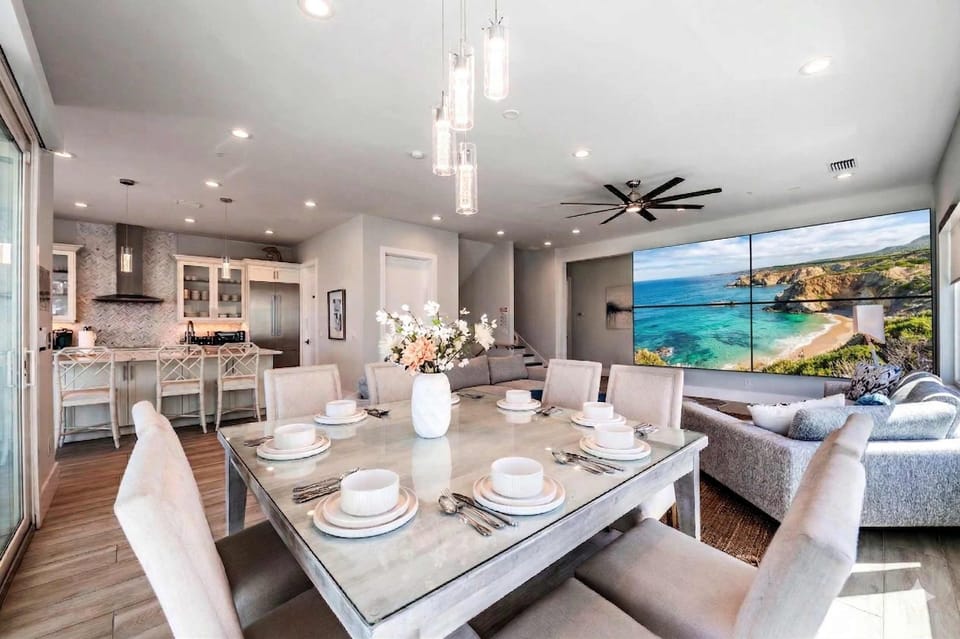 Gather in this bright, open-concept living space featuring a stylish dining area, modern kitchen, and cozy lounge with large TV. Elegant décor, ample seating, and natural light create the perfect setting for meals, relaxation, and memorable stays!