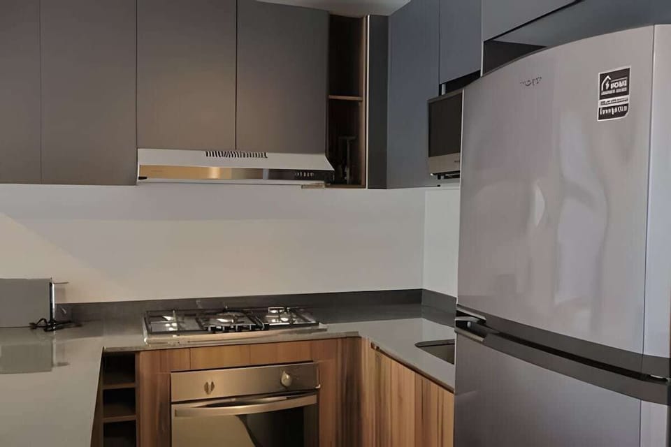 Compact kitchen w/ stainless appliances, cooktop & clean modern finishes