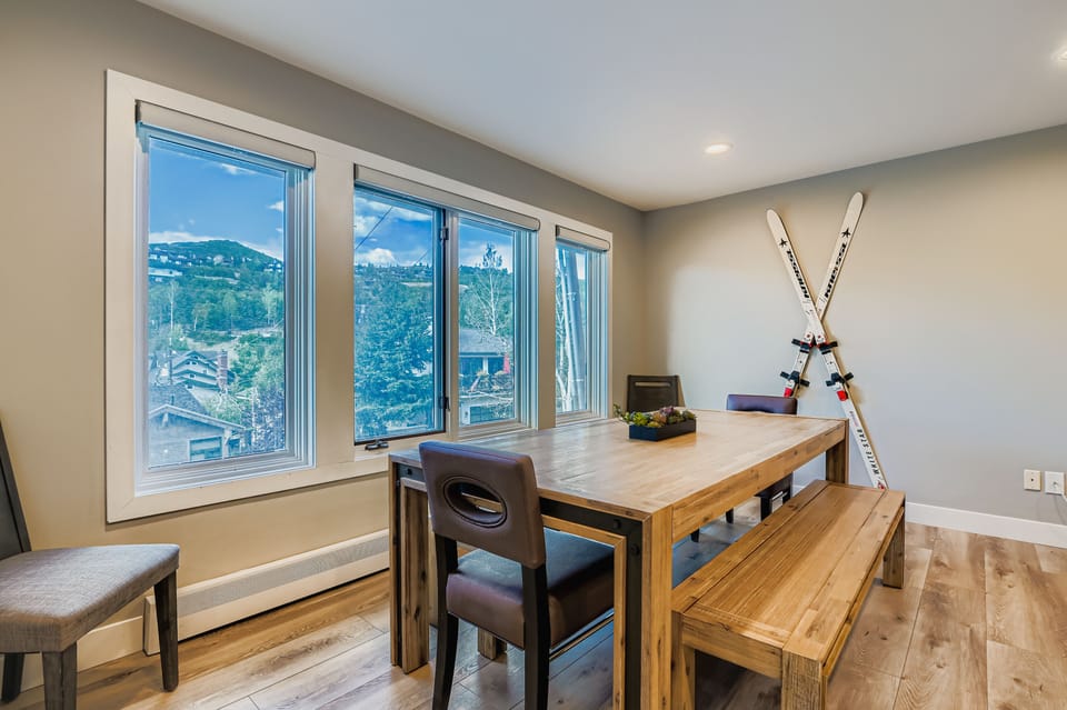 Gather for meals around the large wooden dining table and bench. Enjoy mountain views from the expansive windows. Perfect for your Park City mountain retreat.