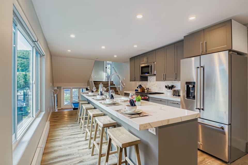 Enjoy a fully stocked kitchen with sleek quartz countertops and a large island, perfect for gathering. Prepare gourmet meals with stainless steel appliances during your Park City getaway.