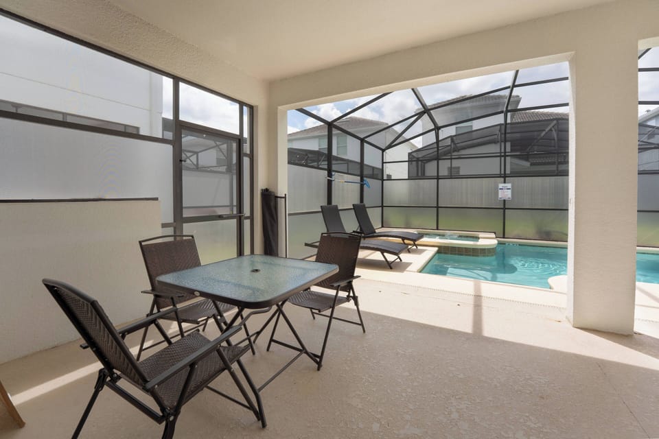 Step into your own private oasis with this screened-in patio, featuring a glass-top table and sleek chairs, perfect for morning coffee or evening chats. Enjoy the sun’s warmth while overlooking the inviting pool just steps away.