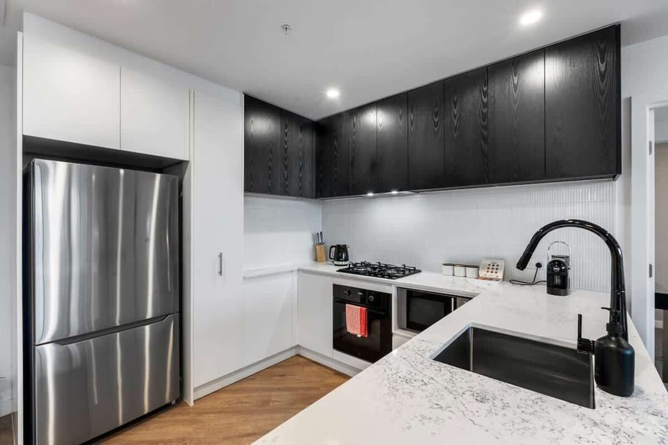Kitchen from another angle – Bright, functional space with stainless-steel fridge, gas cooktop, oven, and dishwasher.