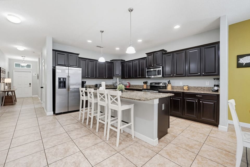 Wide kitchen view with bar seating & fridge