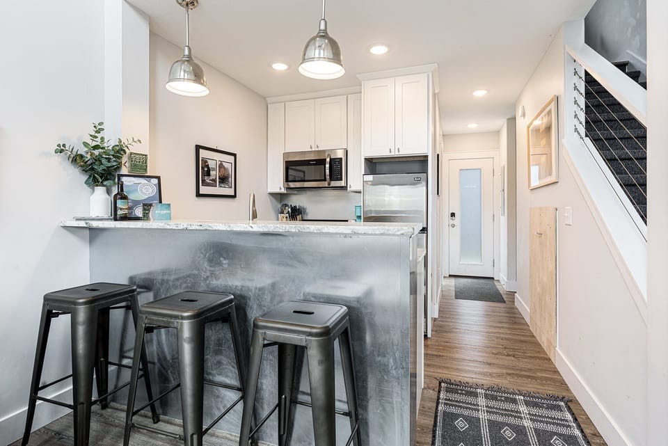 Modern kitchen w/ island seating, pendant lights & open flow to the hall.