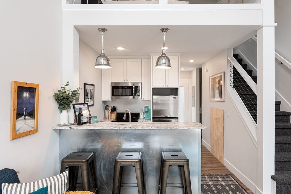 Sleek kitchen w/ island seating & pendant lights—perfect for coffee or late-night bites.