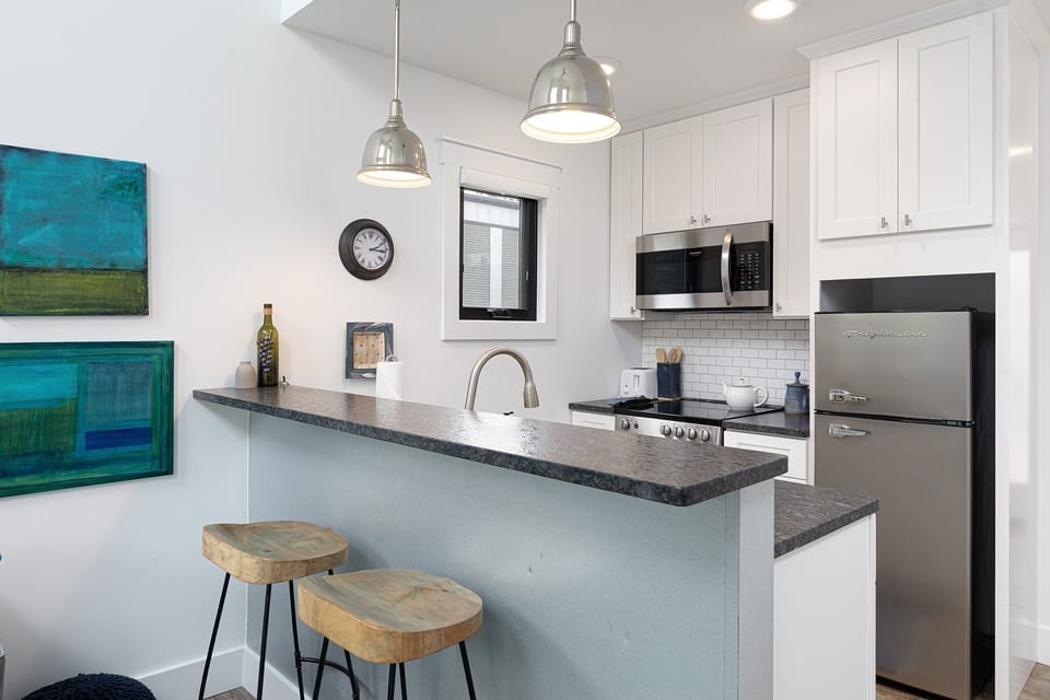 Sleek kitchen w/ bar seating, pendant lighting & stainless steel appliances for easy meals at home.
