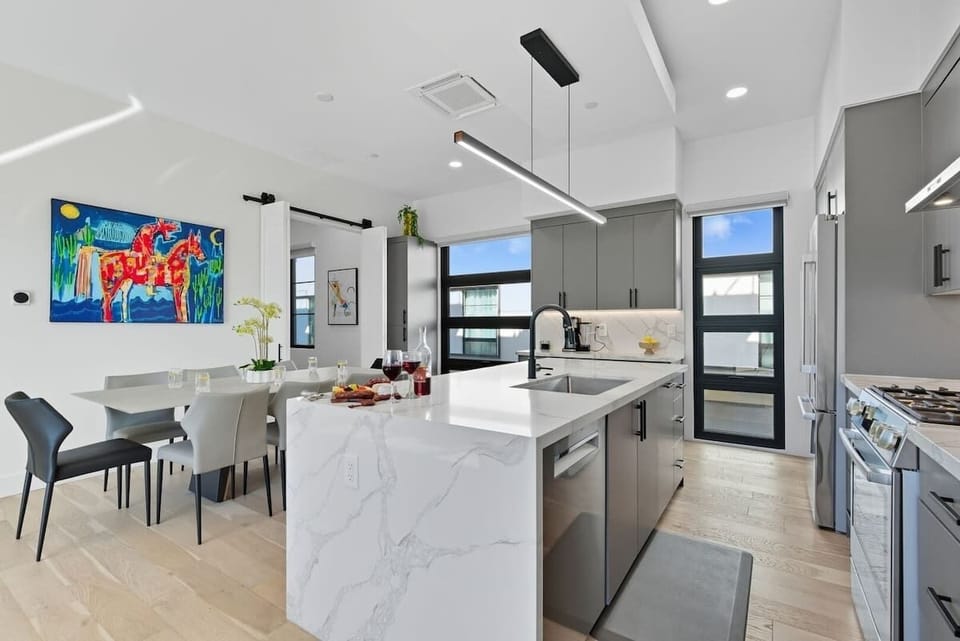 Fully equipped kitchen with stainless steel appliances, a sleek kitchen island with a breakfast bar for casual seating for 4, plus a large dining table for 8. (2nd Floor)