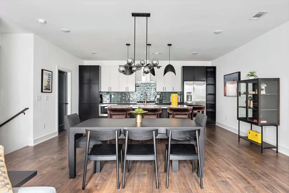 The open layout keeps the cook in the conversation while the kitchen's dark cabinetry and green tile backsplash anchor the whole gathering space