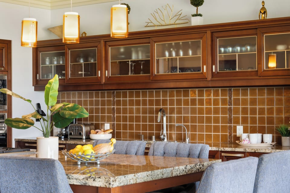 This warm, welcoming kitchen features a granite island with seating for six, rich wood cabinetry, and cozy lighting—perfect for casual breakfasts or lively evening chats.