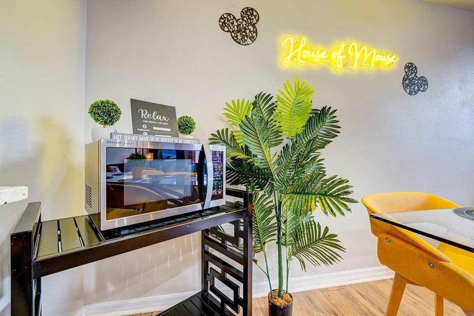 A modern dining area with a microwave and decorative neon sign for a cozy stay.