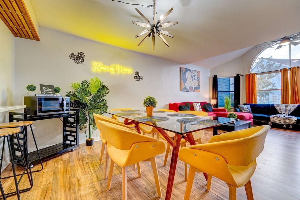 Bright dining area with yellow chairs and a glass table in a family-friendly living space.