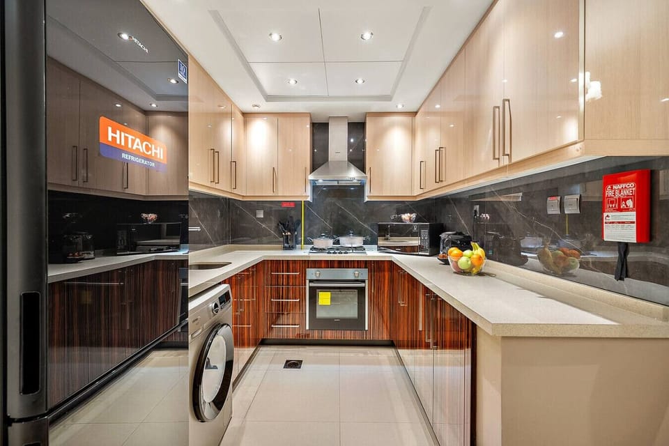 Glossy U-shaped kitchen with modern appliances and under-cabinet lighting.