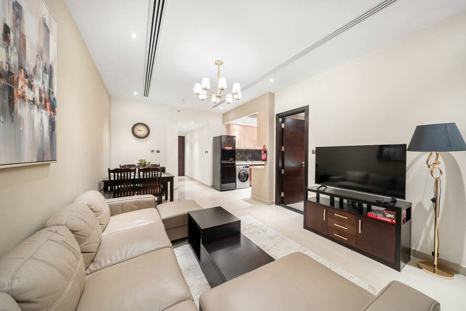 Open-plan living space with kitchen, TV unit, and hallway in view.