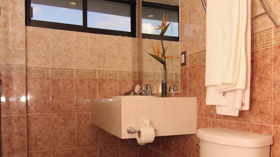 Enjoy a clean, tiled bath with bright mirror and towels.