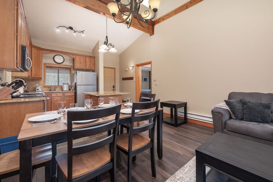Gather around your dining table for memorable meals, then relax on the plush sofa in this open-concept space with rustic beams overhead.