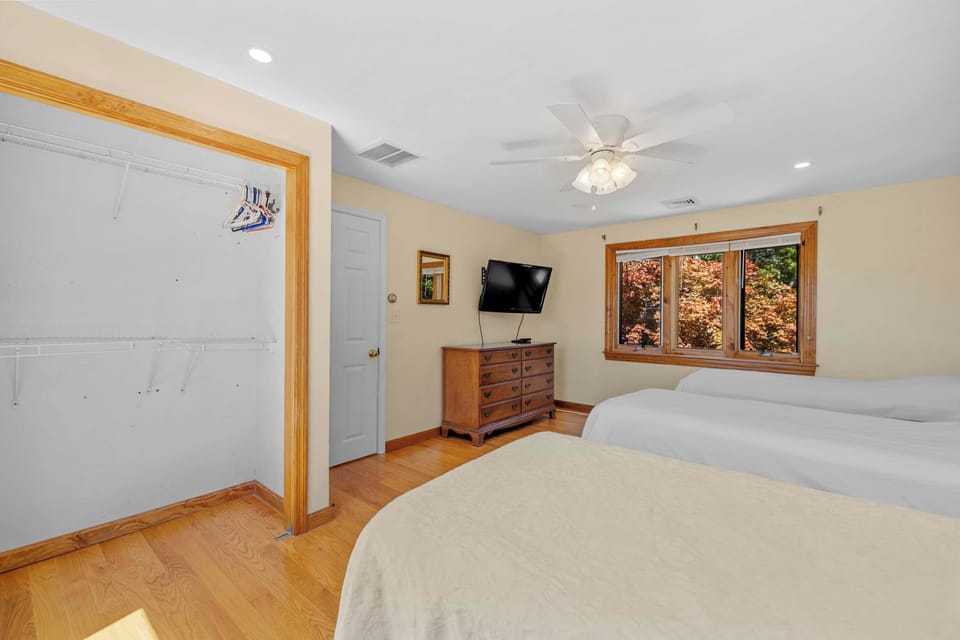 Twin bedroom with ceiling fan, TV, and dresser for storage