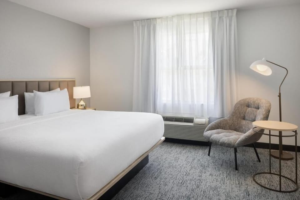 Unwind in crisp linens beside soft light and calm tones.