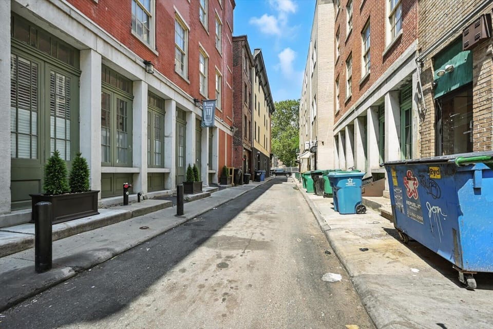 Experience the city from a different perspective. This photo highlights the classic brick buildings and the bustling nature of a city street, with multiple dumpsters and business storefronts.