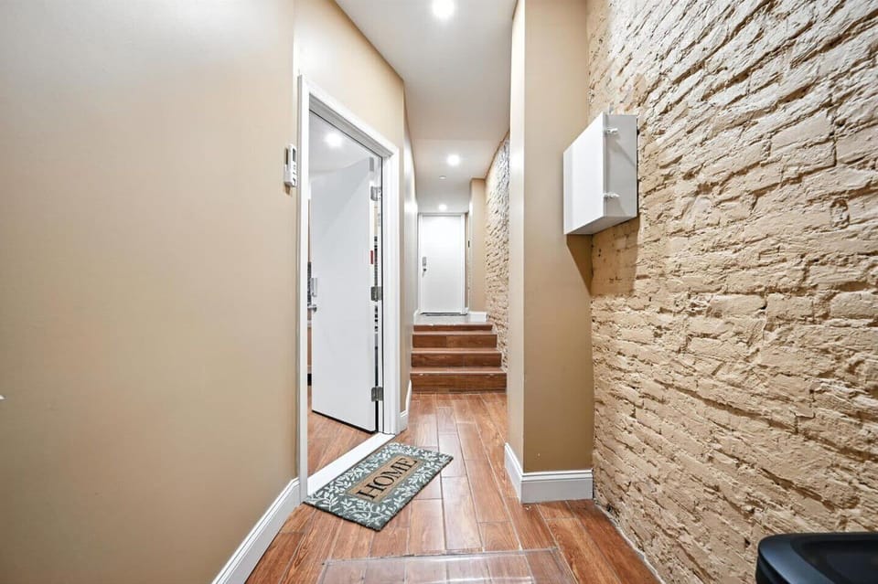 Step into a space with character. The inviting hallway features a striking exposed brick wall and warm wooden floors, creating a unique and welcoming first impression.