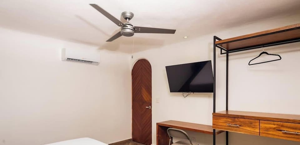 Habitación con ventilador de techo, tv plana, clóset, escritorio y minisplit