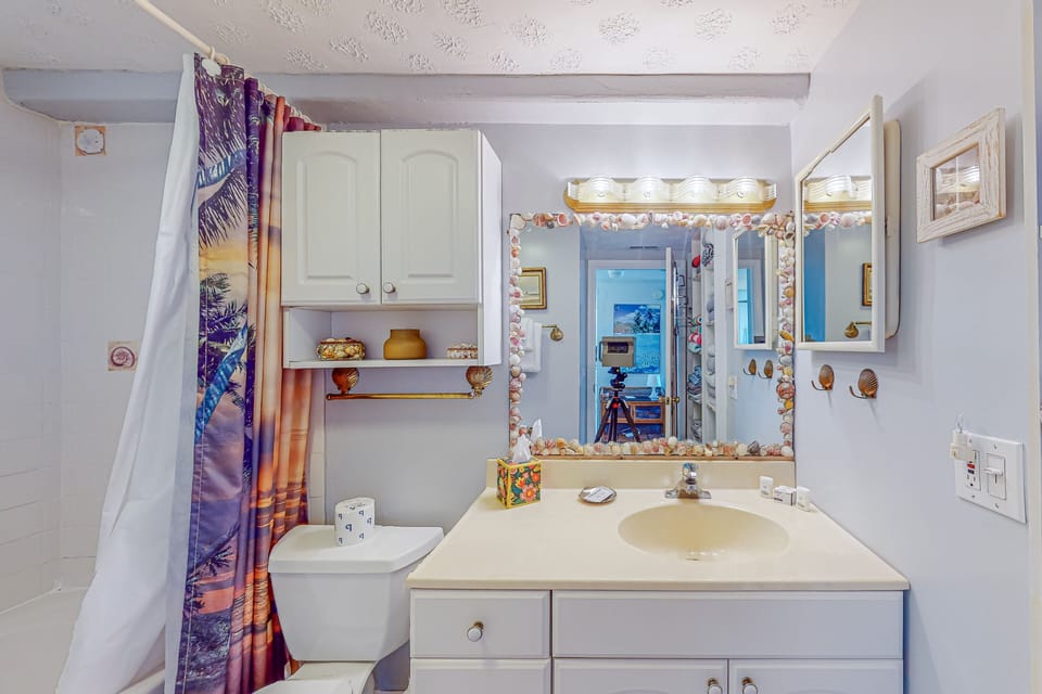 Cozy bathroom with a tub/shower combo, coastal décor accents, and bright natural light for a clean, beachy feel.