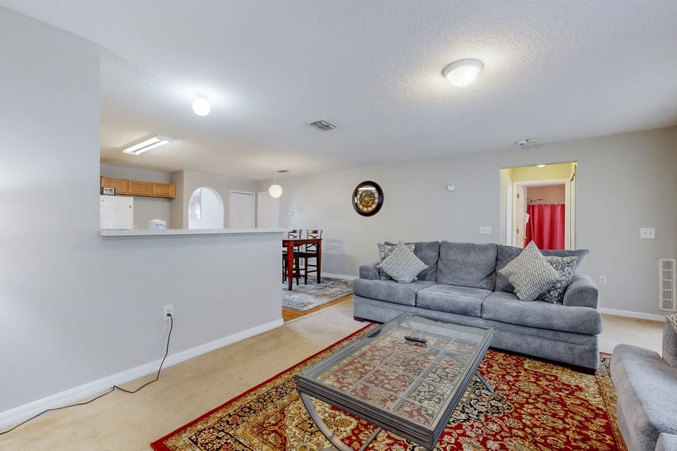 Spacious family room with two sofas, streaming TV, and bright open layout—featuring a door that leads to a relaxing screened-in patio area.