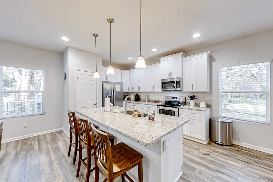 Fully equipped with premium stainless steel appliances, crisp white cabinetry, granite countertops, and a breakfast bar perfect for morning coffee.