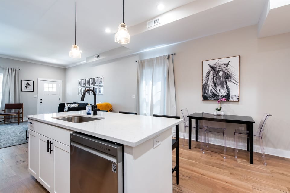 Enjoy the seamless flow from the pristine white kitchen island directly to the modern dining setup. The striking horse artwork watches over the space to celebrate our city heritage.