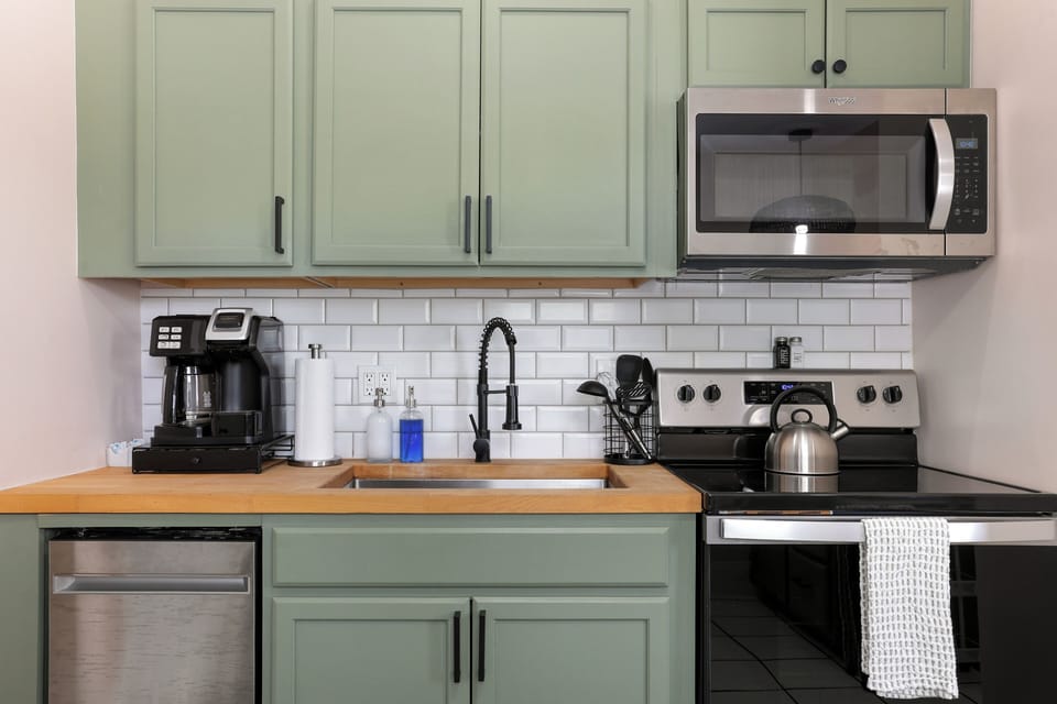The kitchen is fully equipped with new appliances and a soft green finish.
