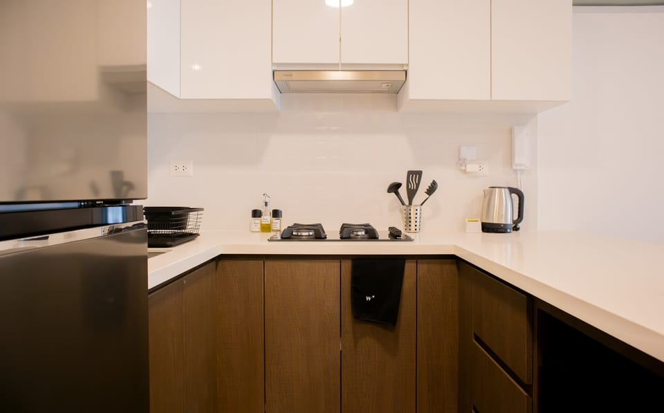 Compact kitchen with white upper cabinets, wooden lower cabinets, and modern appliances.