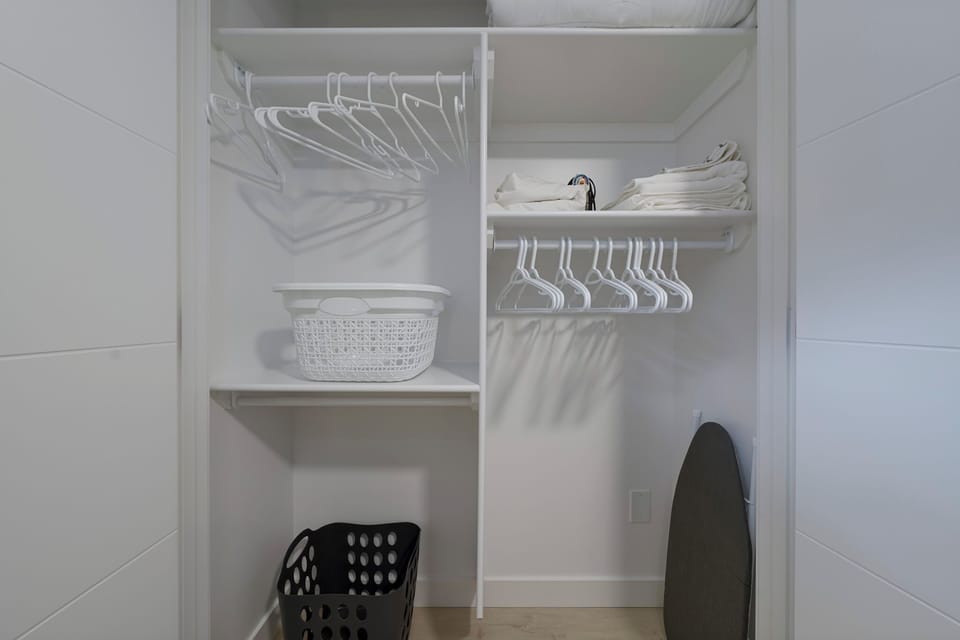 Spacious bedroom with closet, blackout blinds, and smart TV across from bed.