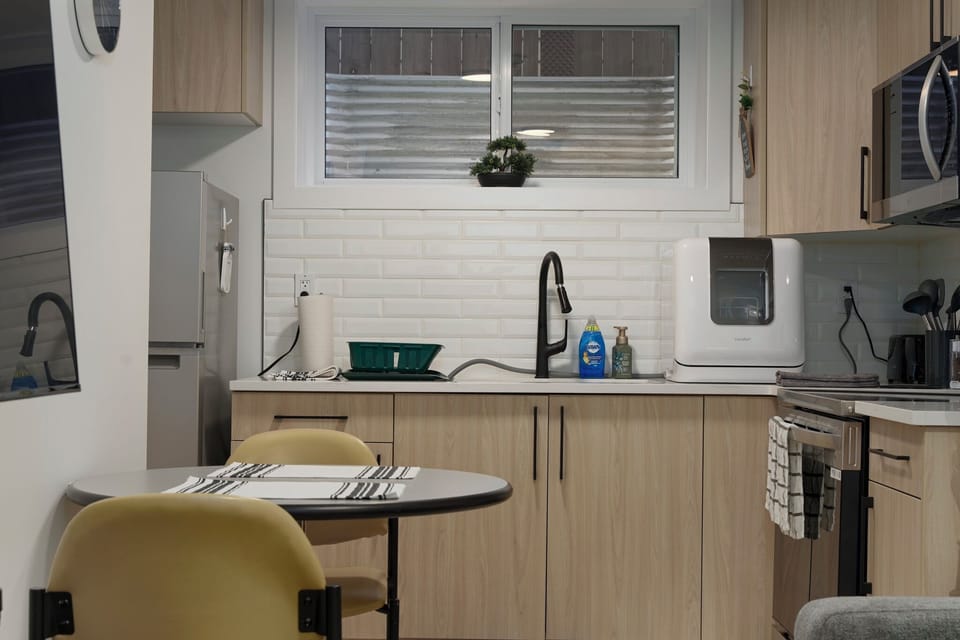Bright kitchen with essentials, dish rack, countertop dishwasher, and seating.