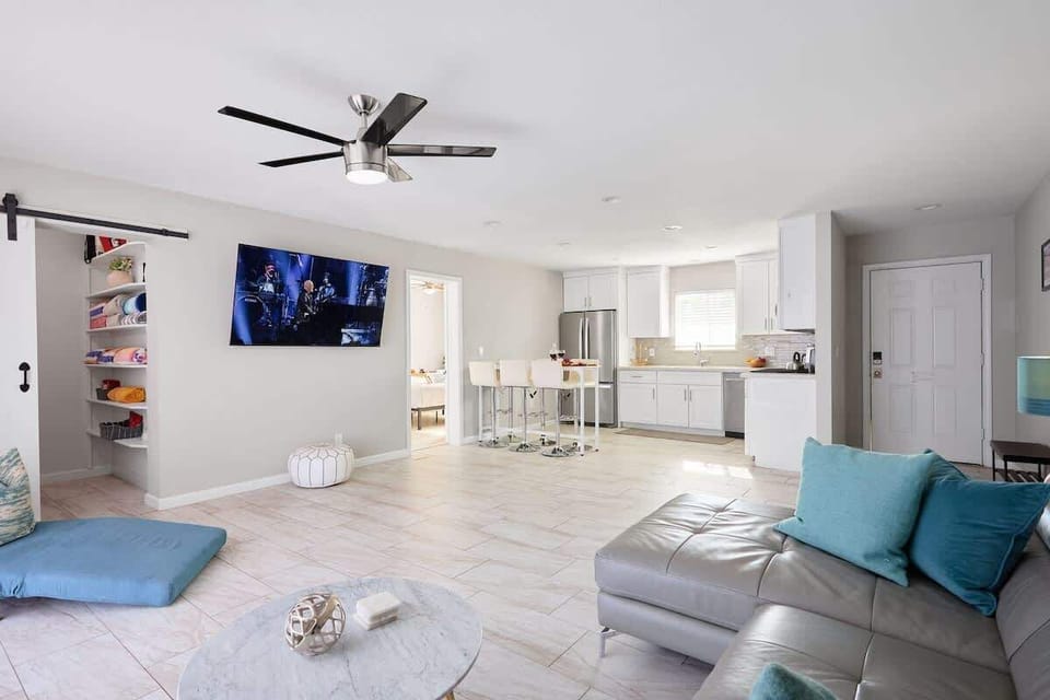 Open-concept living room with a cozy sectional, Smart TV, and sliding glass doors filling the space with natural light.