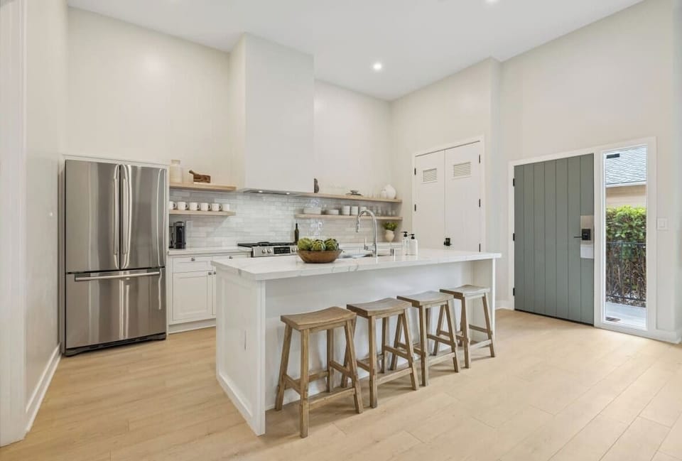 Modern kitchen with a white island, bar seating, and open shelving