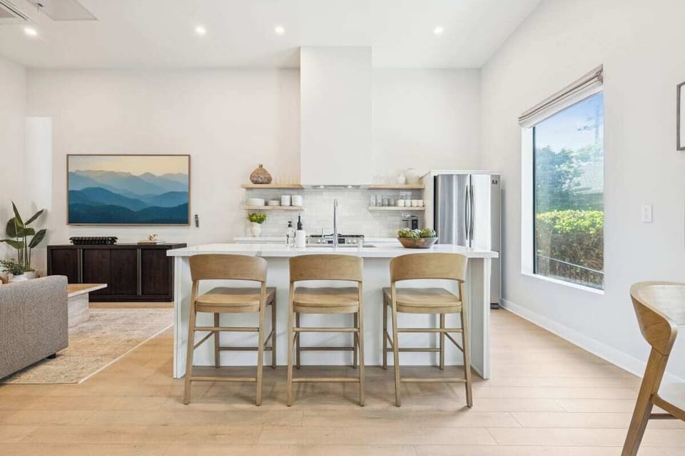 Modern kitchen with a white island, bar seating, and open shelving.