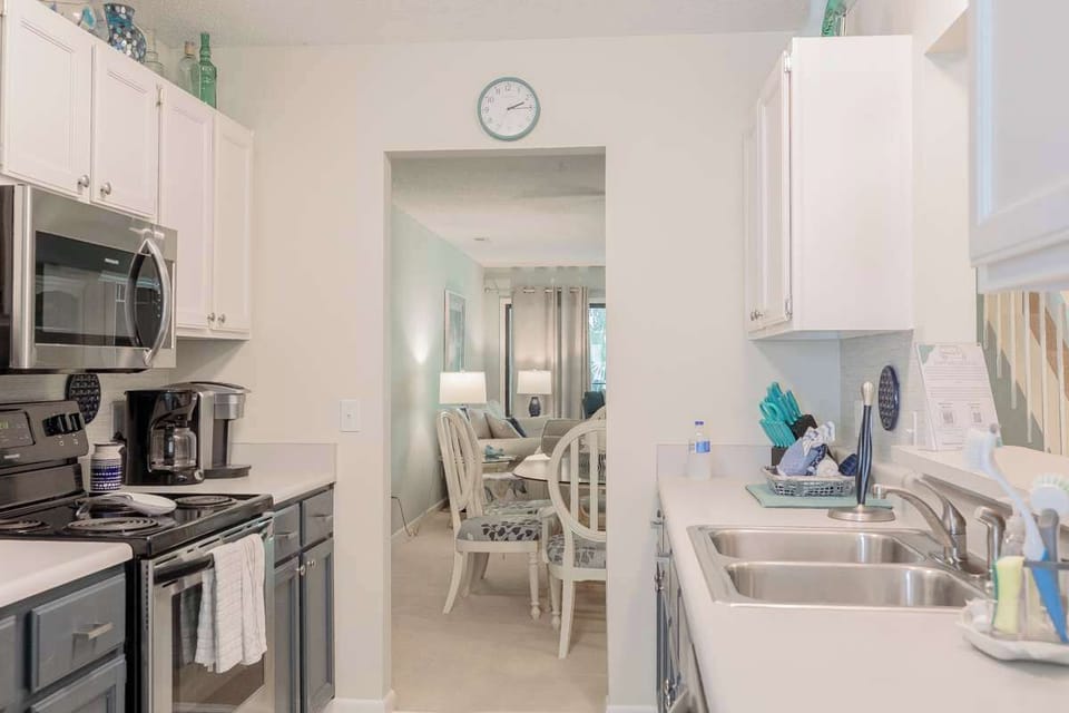 Bright and welcoming, this Hilton Head condo kitchen features fun blue cabinets paired with sleek stainless steel appliances. An additional dining area offers extra space for family meals, morning coffee, or game nights after a day at the beach.