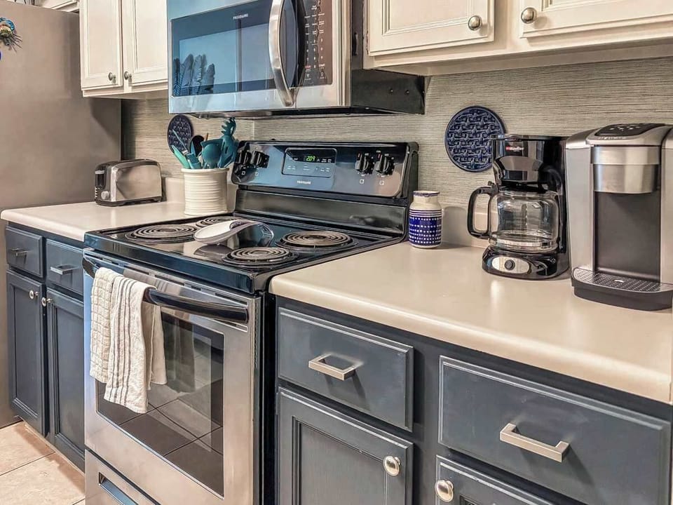 Kitchen featuring a microwave, Keurig coffee maker, oven, and a full set of cooking utensils—everything you need to prepare meals and enjoy your Hilton Head getaway with all the comforts of home.