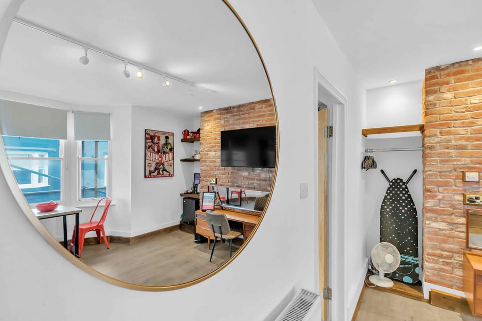 A bright living room with a bed, dining table, workstation and spacious open area 
