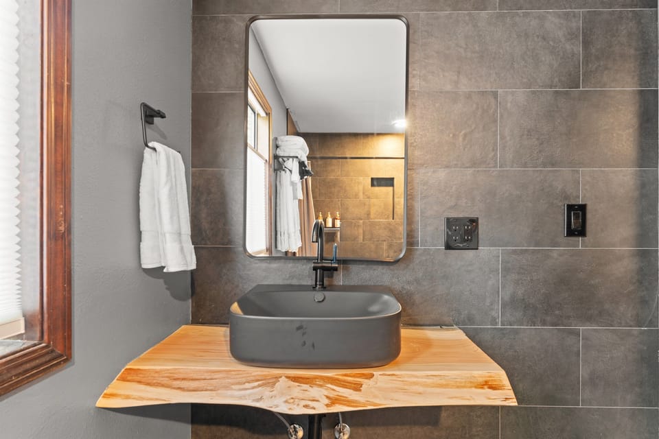 Primary Bathroom: Experience sleek design with a modern sink and natural wood accents!