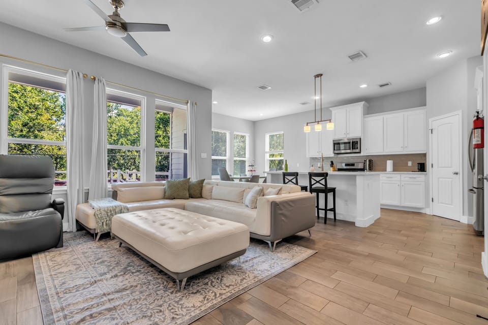 Bright living room with comfy sofa, wood floors & sunny windows.
