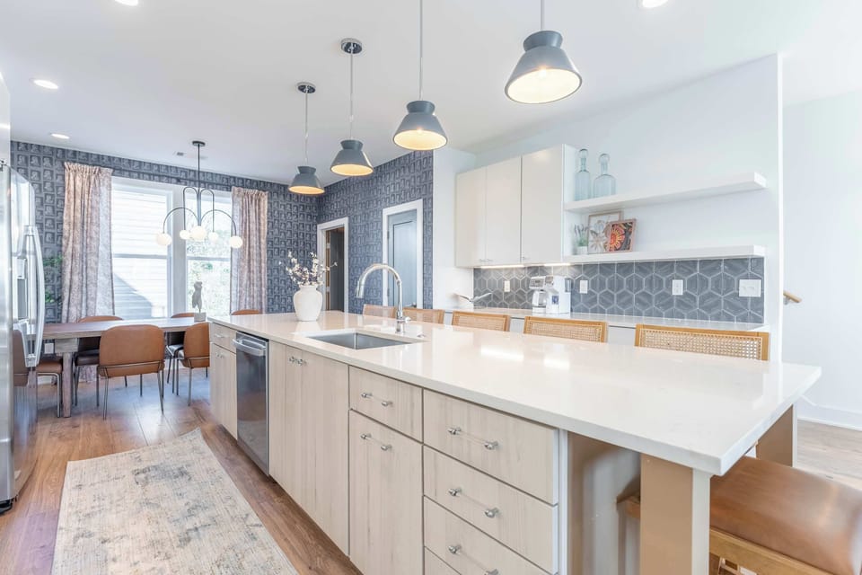 Island kitchen with a sink and dishwasher flows into the dining area, prep and eating happening in one open sightline