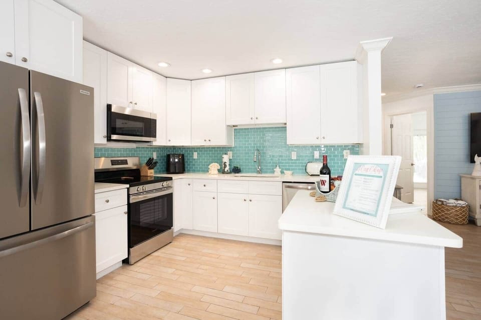 Breezy open-concept kitchen—stainless elegance and a sea-glass backsplash that wows.