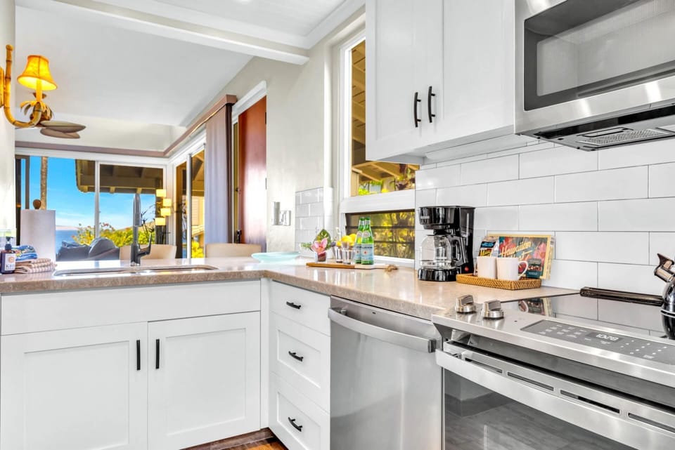 Bright kitchen with modern appliances, bar seating, and surrounded by windows with island views. 