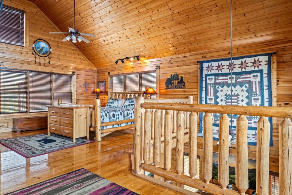 Wake up surrounded by windows and mountain light in this open loft bedroom with warm wood finishes, rustic touches, and extra space to relax.