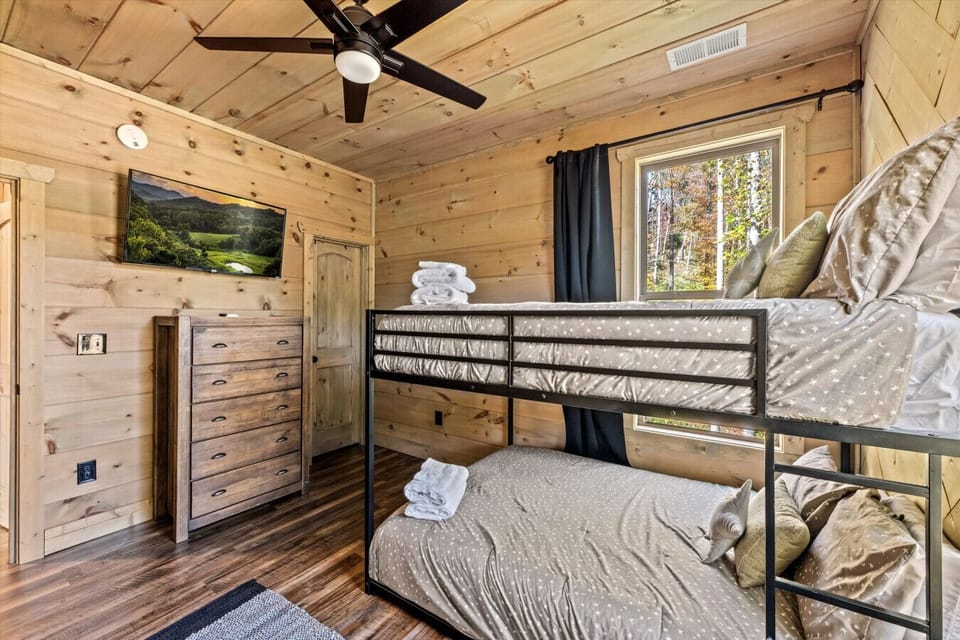 This peaceful bunk room is made for rest and play—tucked under cozy star-covered bedding, with a big window and a TV to wind down after a full day.