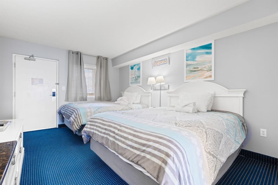 Bedroom with two queen beds, a smart tv, night stand, two dressers, and a closet for personal effects.