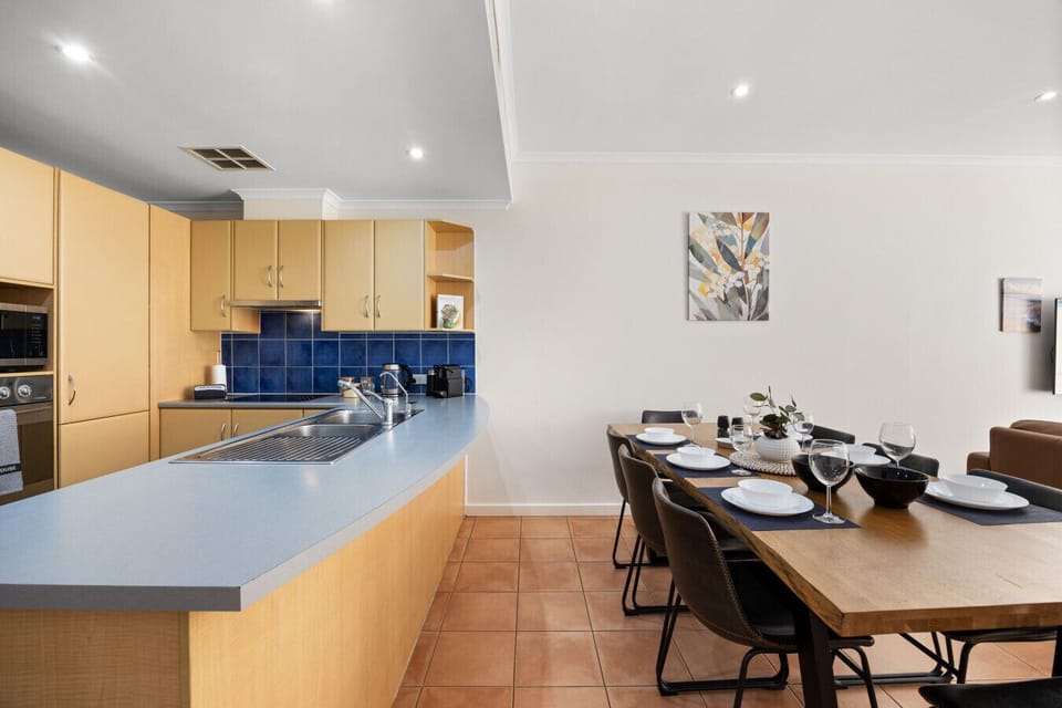 Gather with ease in this open-plan kitchen and dining space, where a generous breakfast bar and fully equipped kitchen flow seamlessly to a table set for shared meals and relaxed conversation.