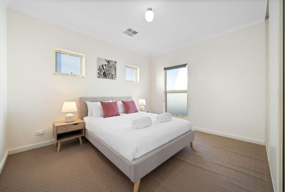 A cosy third bedroom with a comfortable queen bed, fresh linen, and a calm, light-filled feel for a restful night’s sleep.